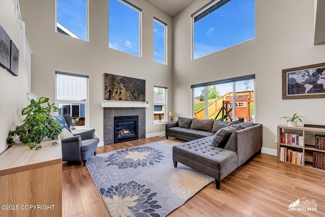 2945 Morgan Loop, Anchorage, AK 99516 - living area featuring a tiled fireplace, light wood-style floors, a high ceiling, and baseboards