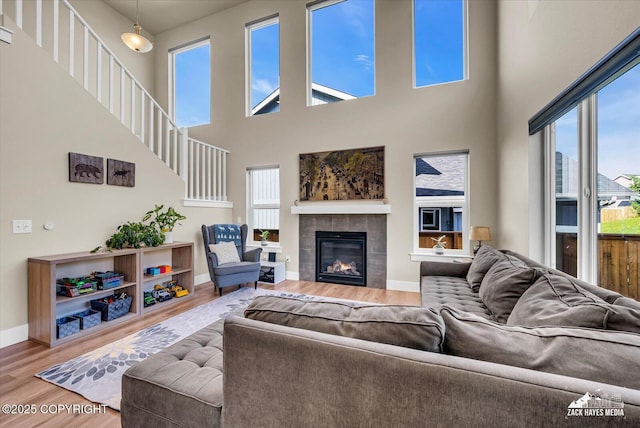 2945 Morgan Loop, Anchorage, AK 99516 - living area featuring wood finished floors, baseboards, a tiled fireplace, a towering ceiling, and stairs