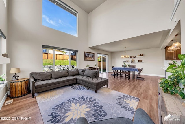 2945 Morgan Loop, Anchorage, AK 99516 - living room with a chandelier, a towering ceiling, light wood-type flooring, and baseboards