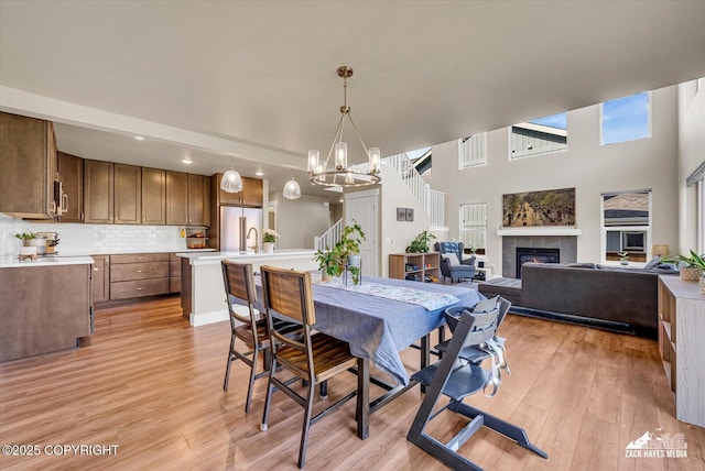 2945 Morgan Loop, Anchorage, AK 99516 - dining space with a chandelier, a fireplace, light wood finished floors, recessed lighting, and a towering ceiling