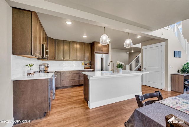 2945 Morgan Loop, Anchorage, AK 99516 - kitchen with stainless steel appliances, backsplash, light countertops, light wood-style floors, and pendant lighting