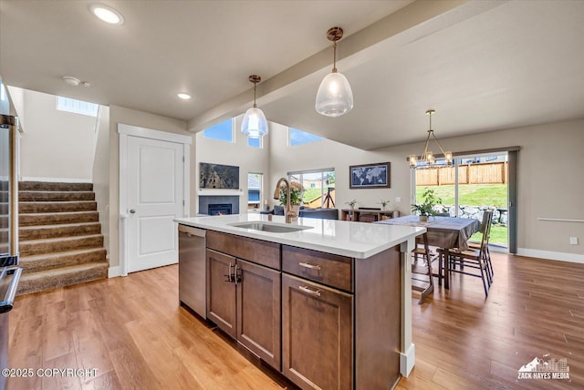 2945 Morgan Loop, Anchorage, AK 99516 - kitchen featuring dishwasher, a sink, a fireplace, light countertops, and hanging light fixtures