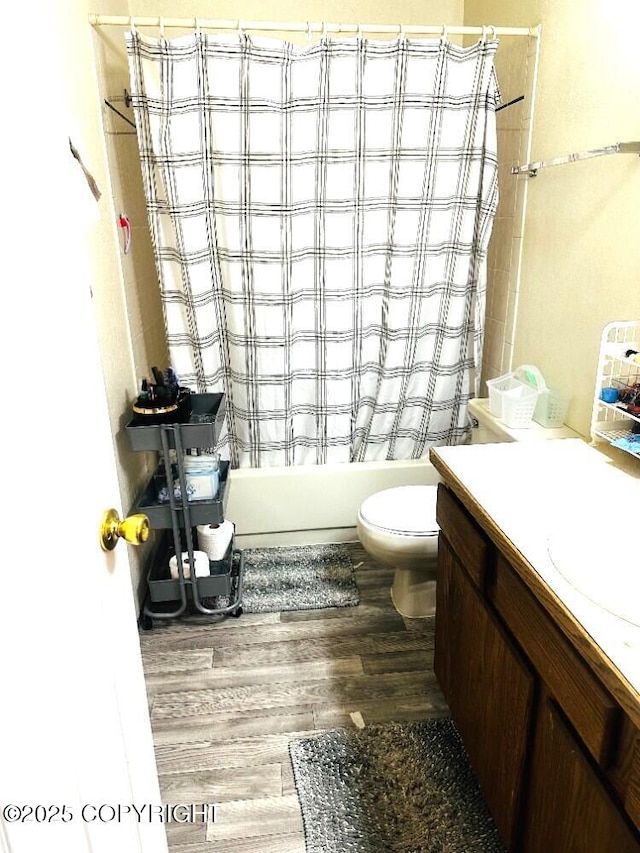 bathroom featuring wood finished floors, shower / bathtub combination with curtain, toilet, and vanity