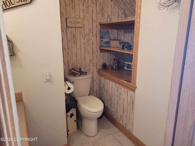 bathroom with wood walls, toilet, and tile patterned floors