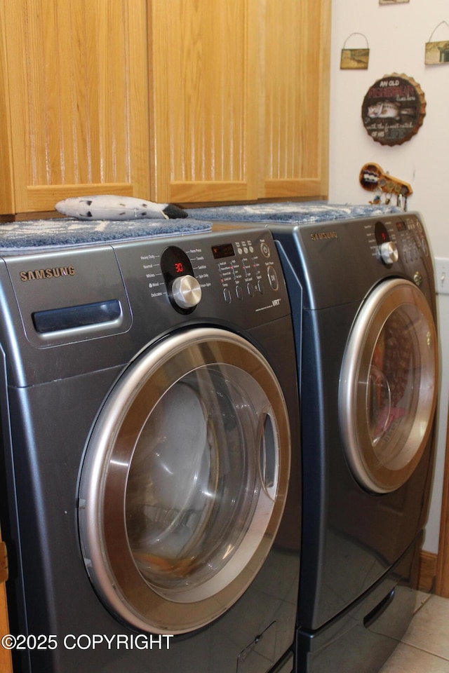 laundry room featuring washer and clothes dryer, tile patterned floors, and cabinet space