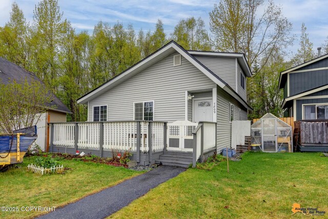 rear view of property featuring an exterior structure, an outdoor structure, a deck, and a yard