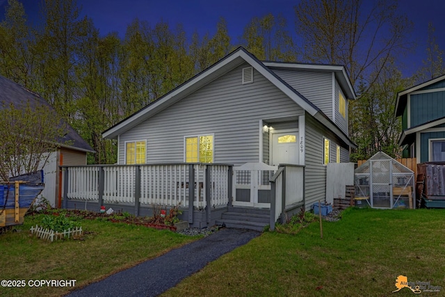 view of front facade featuring an exterior structure, an outbuilding, a front lawn, and a deck