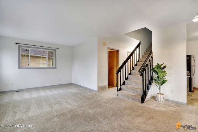 unfurnished living room featuring carpet floors, stairway, and baseboards