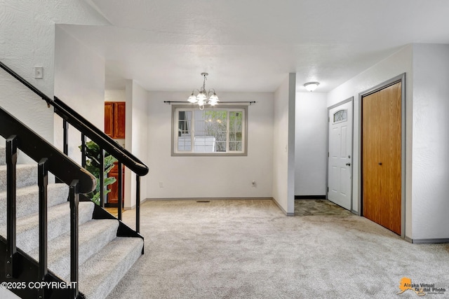 carpeted foyer entrance featuring a chandelier, stairway, and baseboards
