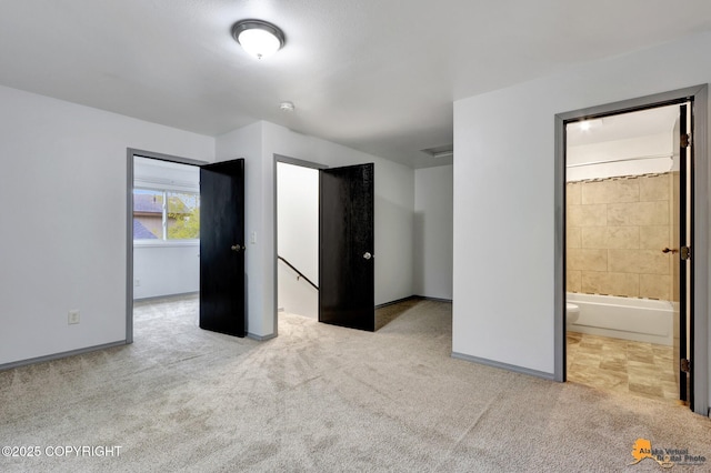 unfurnished bedroom featuring carpet, baseboards, and ensuite bath
