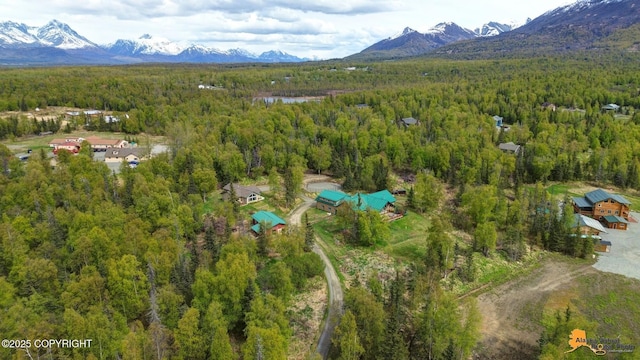 aerial view of property and surrounding area featuring a heavily wooded area and mountains