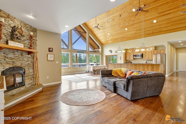 living room featuring high vaulted ceiling, baseboards, hardwood / wood-style flooring, a fireplace, and recessed lighting