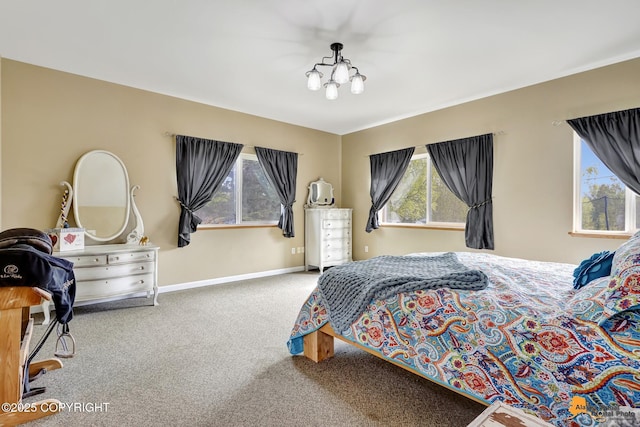 carpeted bedroom featuring baseboards and a chandelier