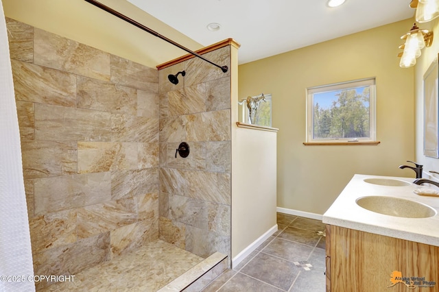bathroom featuring tiled shower, tile patterned floors, baseboards, recessed lighting, and double vanity