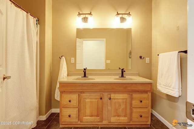 full bath featuring double vanity, tile patterned floors, and baseboards