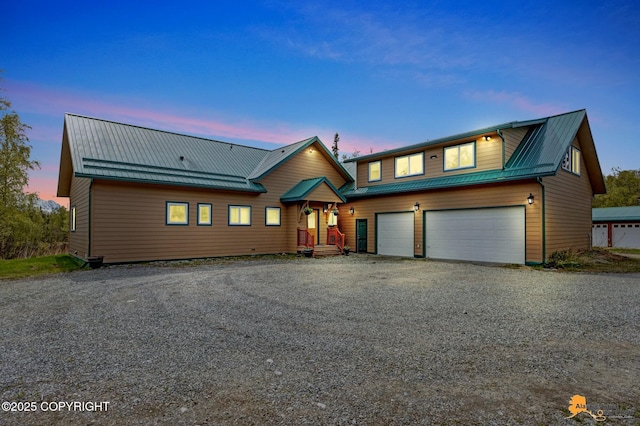 chalet / cabin with metal roof, gravel driveway, and an attached garage