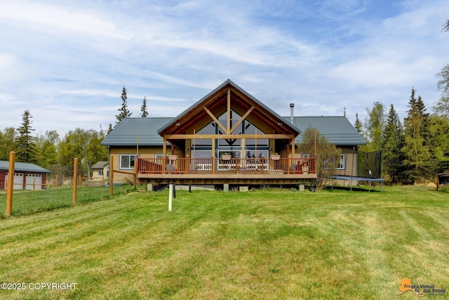 back of property with a deck, a yard, a trampoline, and metal roof