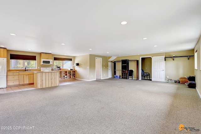 unfurnished living room featuring a sink, light colored carpet, baseboards, and recessed lighting