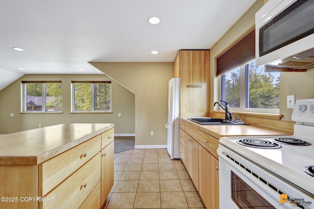 kitchen featuring white appliances, a sink, light brown cabinetry, recessed lighting, and light countertops