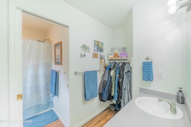 bathroom with a sink, wood finished floors, and baseboards