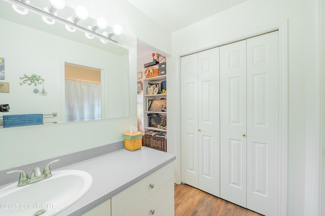 bathroom with a closet, vanity, and wood finished floors