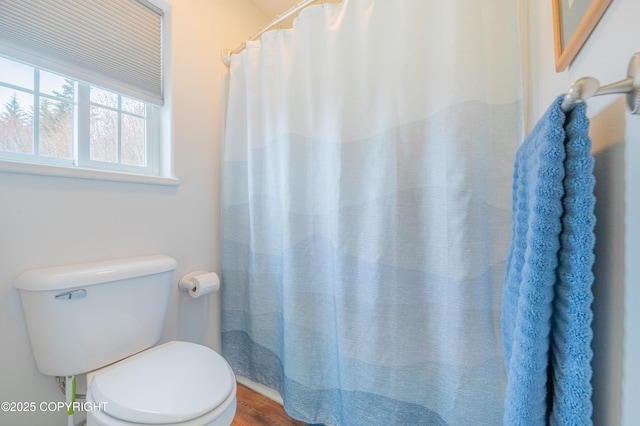 bathroom with toilet, wood finished floors, and a shower with shower curtain