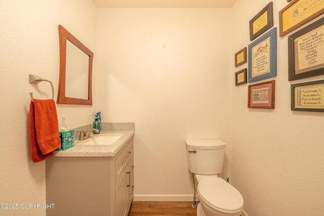 bathroom featuring vanity, wood finished floors, toilet, and baseboards