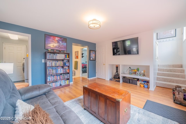 living area featuring wood finished floors, stairs, and baseboards