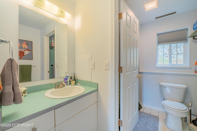 bathroom with toilet, vanity, and baseboards