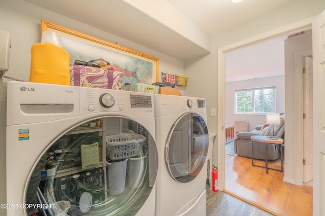 laundry room with washer and dryer and wood finished floors