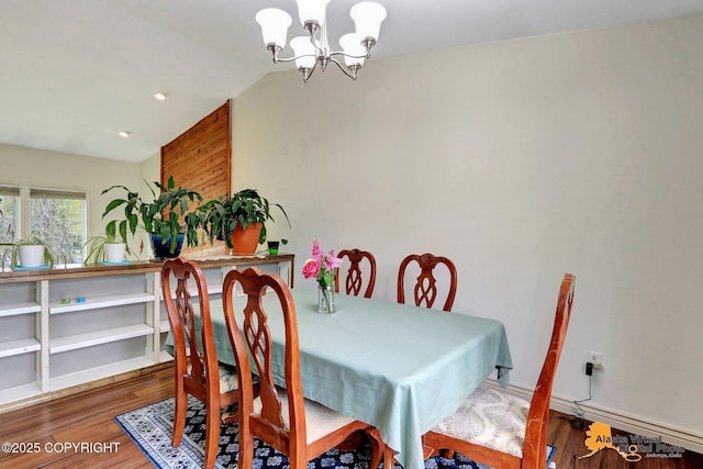 dining space with a chandelier, wood finished floors, and vaulted ceiling
