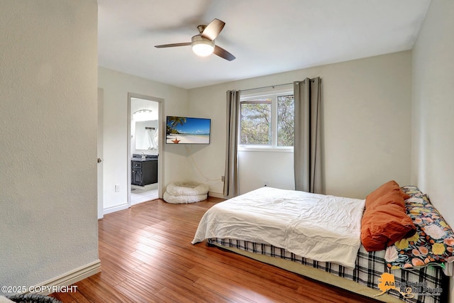 bedroom with baseboards, wood finished floors, connected bathroom, and ceiling fan