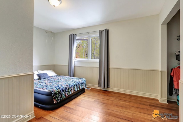 bedroom with wood finished floors and wainscoting