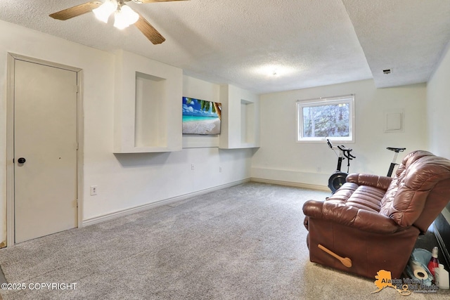 living area with a textured ceiling, carpet flooring, a ceiling fan, and baseboards