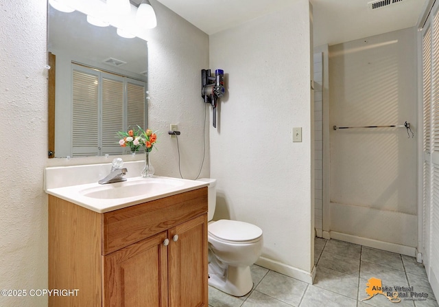 full bathroom featuring tile patterned floors, toilet, vanity, a textured wall, and baseboards