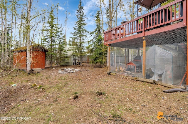 view of yard featuring an outbuilding, exterior structure, a storage shed, and a deck