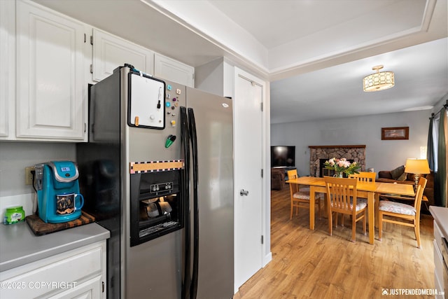 kitchen with refrigerator with ice dispenser, white cabinets, light wood finished floors, and open floor plan