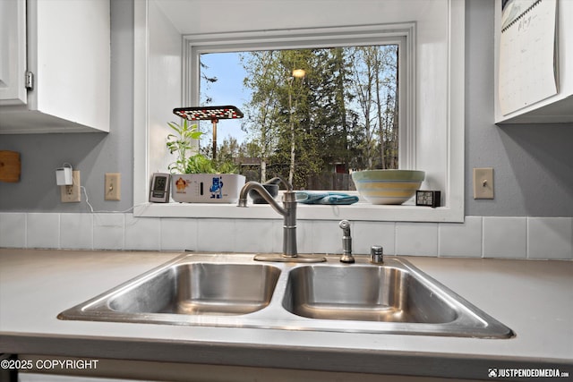 kitchen view of a sink, light countertops, and white cabinets