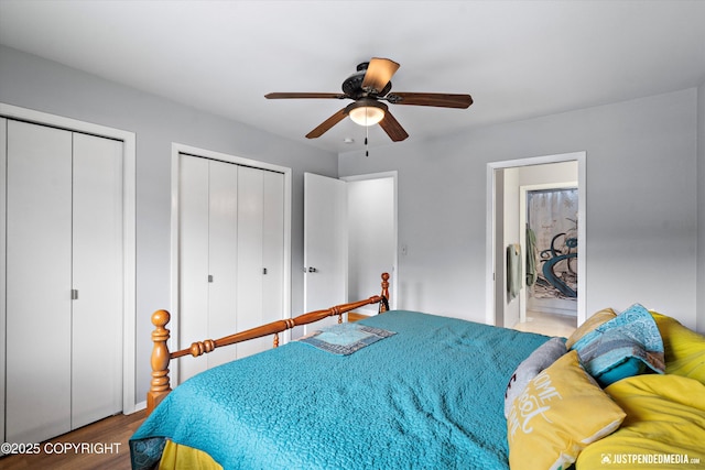 bedroom featuring two closets, wood finished floors, and ceiling fan
