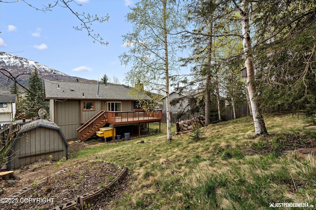 view of yard featuring a deck with mountain view, stairs, and an outdoor structure