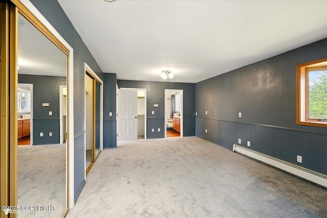 4035 S Tustin Dr, Palmer, AK 99645 - unfurnished bedroom featuring a baseboard radiator, carpet floors, ensuite bath, multiple closets, and a wainscoted wall