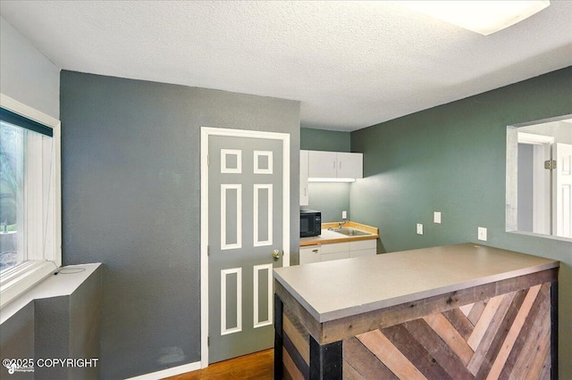 4035 S Tustin Dr, Palmer, AK 99645 - kitchen with black microwave, white cabinetry, a sink, a peninsula, and light countertops