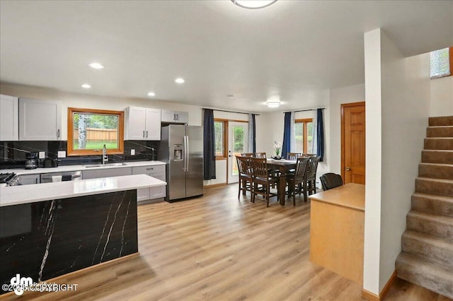 4320 Seeley Cir, Anchorage, AK 99502 - kitchen with stainless steel refrigerator with ice dispenser, a sink, light countertops, backsplash, and light wood-type flooring