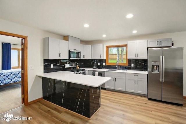 4320 Seeley Cir, Anchorage, AK 99502 - kitchen with stainless steel appliances, a sink, light wood finished floors, a peninsula, and light countertops