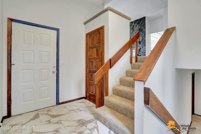 foyer entrance featuring marble look tiles, stairway, and baseboards