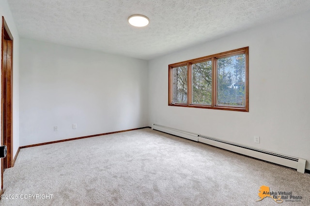carpeted spare room with a baseboard heating unit, a textured ceiling, and baseboards