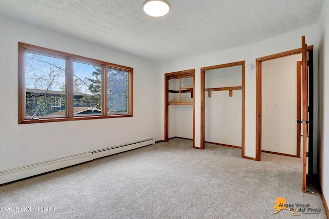 unfurnished bedroom with baseboard heating, multiple closets, light colored carpet, a textured ceiling, and baseboards