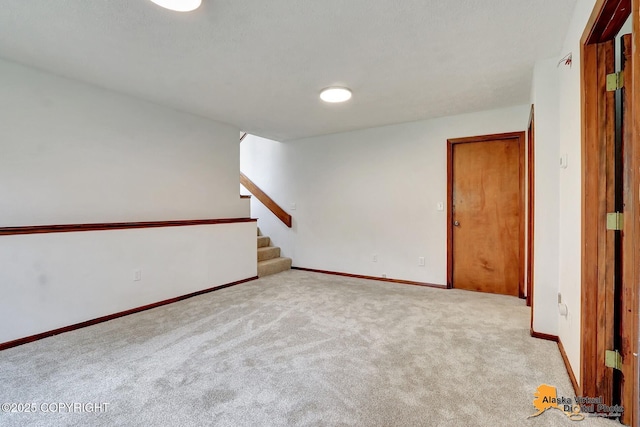 spare room featuring carpet, stairway, and baseboards