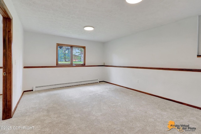 spare room with baseboard heating, carpet, baseboards, and a textured ceiling