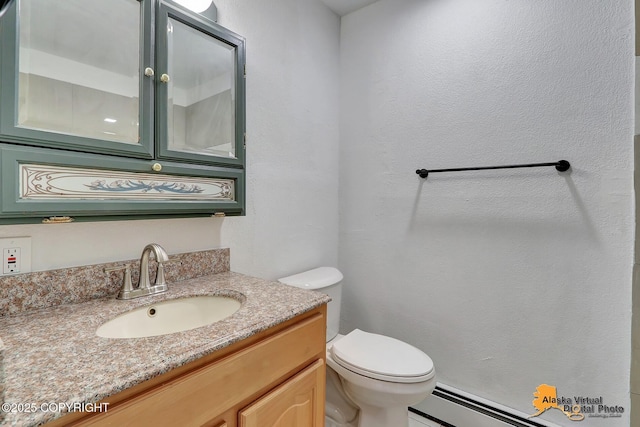 bathroom featuring toilet, a baseboard heating unit, and vanity